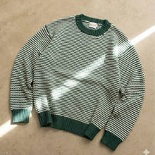 Load image into Gallery viewer, Green and white striped sweater on a beige surface