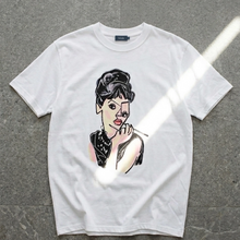 Load image into Gallery viewer, White t-shirt with a graphic of a stylized face on a gray background