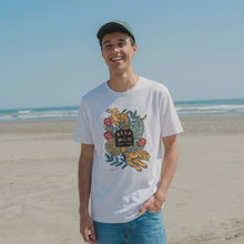 Load image into Gallery viewer, Person wearing a white t-shirt with a graphic design on a beach
