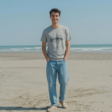 Load image into Gallery viewer, Man standing on a beach wearing a gray t-shirt and blue jeans.