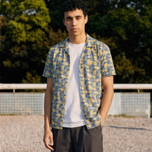 Load image into Gallery viewer, Man wearing a patterned shirt over a white t-shirt outdoors with greenery in the background