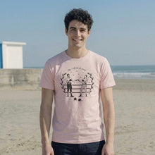 Load image into Gallery viewer, Person wearing a pink t-shirt with a graphic design on a beach