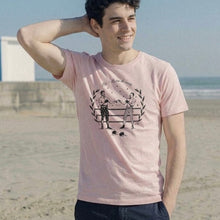 Load image into Gallery viewer, Man wearing a pink t-shirt with a graphic design on a beach