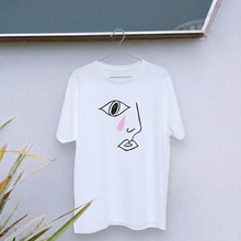 Load image into Gallery viewer, White t-shirt with a minimalist face design on a hanger against a light gray wall.