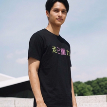 Load image into Gallery viewer, Person wearing a black t-shirt with colorful text outdoors