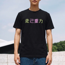 Load image into Gallery viewer, Person wearing a black t-shirt with colorful text outdoors