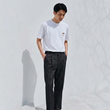 Load image into Gallery viewer, Man wearing a white t-shirt and dark pants against a plain background