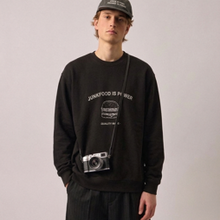 Load image into Gallery viewer, A model wearing a black crewneck sweatshirt with a white graphic print that reads 'SOMETHING IS WRONG' and 'JACK DOGS ARE MY FOOD'. He is also wearing a black cap and a black camera bag.