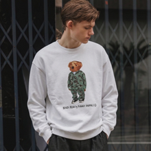 Load image into Gallery viewer, Person wearing a white sweatshirt with a graphic design of a bear in camouflage and text.