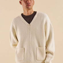 Load image into Gallery viewer, A male model wearing a beige heavy knitted cardigan with a front zip construction. The cardigan is made from a blend of viscose, polyester, and nylon.