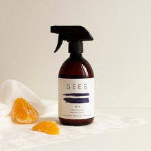 Load image into Gallery viewer, A textile spray bottle with a label reading 'SEES COMPANY' and 'serene bergamot &amp; lemon', placed on a white surface next to a slice of orange.