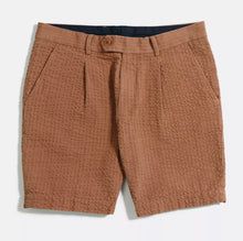 Load image into Gallery viewer, A pair of brown pleat shorts with small front pleats and side seam pockets, featuring a zip fly opening and corozo buttons.